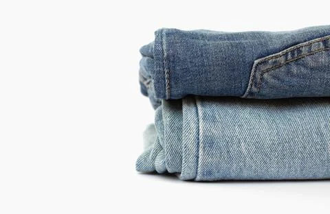 Stack of blue jeans isolated on white background, space for text, close-up Stock Photos