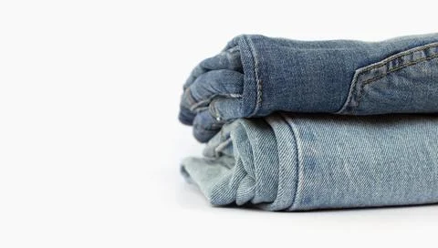 Stack of blue jeans isolated on white background, space for text, close-up Stock Photos