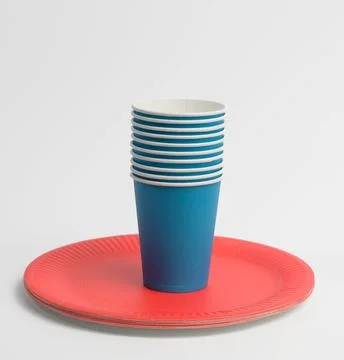 Stack of blue paper cups and red round plates on a white background Stock-Fotos