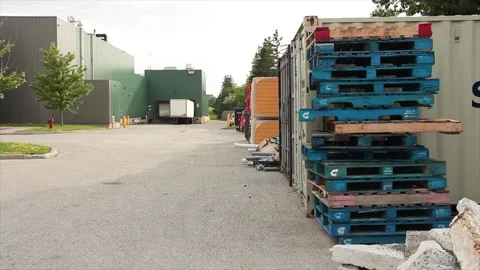 Stack of blue skids with wood colored ones too frame right next to container Video stock 246611531