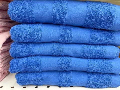 Stack of blue towels on shelf in store, close up view. Stock Photos