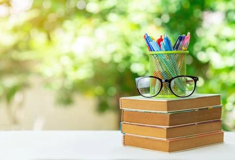 Stack book, glasses and stationery in the garden, out of focus background. Foto stock