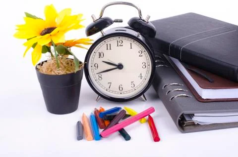 Stack of book with ticking vintage clock, artificial flower plant and colorfu Foto stock