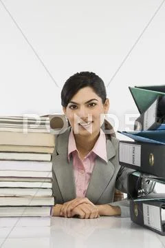 Stack of books and binders in front of a businesswoman at desk Stock Photos