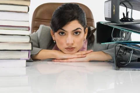 Stack of books and binders in front of a businesswoman at desk Stock Photos