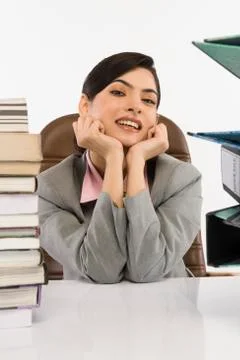 Stack of books and binders in front of a businesswoman at desk Stock Photos