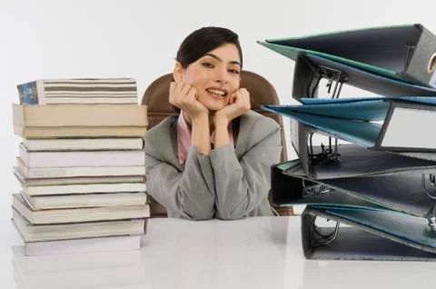 Stack of books and binders in front of a businesswoman at desk 스톡 사진