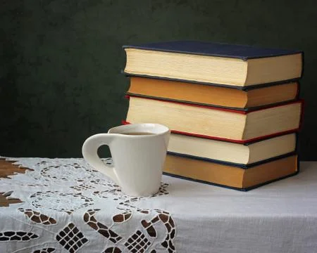 A stack of books and Cup of tea on the table with a white tablecloth. Foto stock