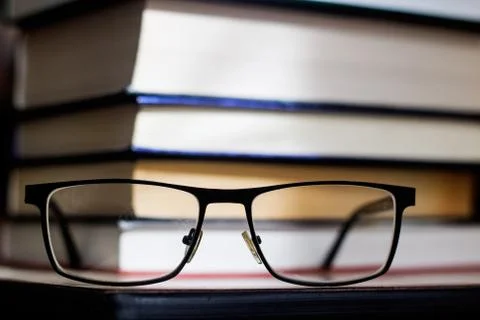 Stack of books and glasses closeup in the dark Stock Photos