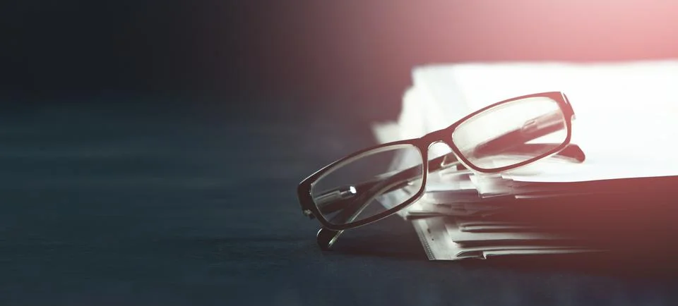 Stack of books and glasses on dark background. Selective focus. Stock Photos