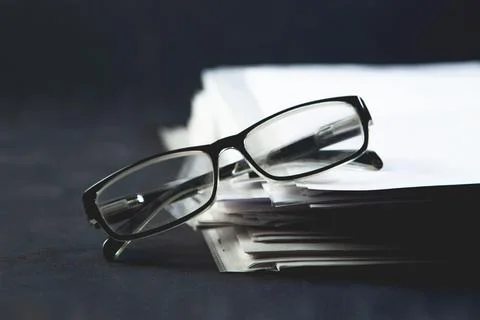 Stack of books and glasses on dark background. Selective focus. Stock Photos