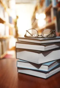 Stack of books and glasses on table in library Stockfoto's