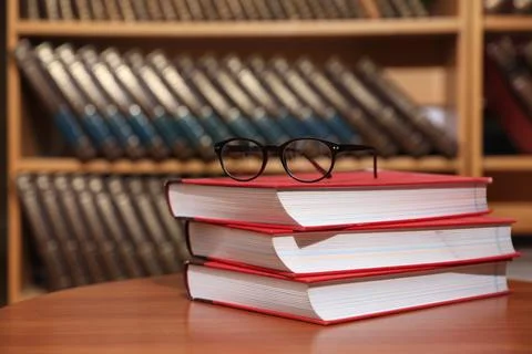 Stack of books and glasses on table in library. Space for text 스톡 사진
