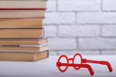 Stack with books and red glasses on the table, education concept, background Stock Photos