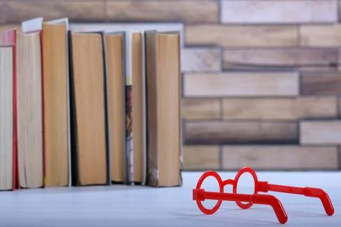 Stack with books and red glasses on the table, education concept, background Stock Photos