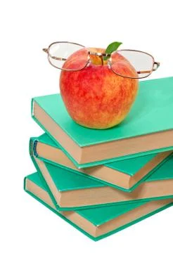Stack of books with an apple and glasses on a white background Stock Photos