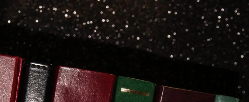 A stack of books on a black background. Many colorful books. Books in a long  库存照片