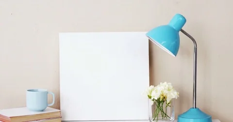 Stack of books, blank board, flower vase, cup of tea and table lamp Stock Footage 77478183