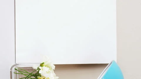 Stack of books, blank board, flower vase, cup of tea and table lamp Stock Footage 300428634