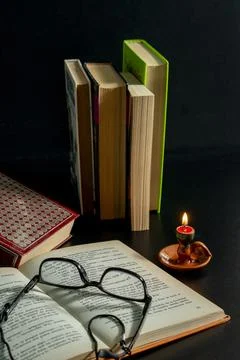 A stack of books with a candle on top of them Stock Photos