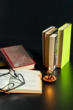 A stack of books with a candle on top of them Stock Photos