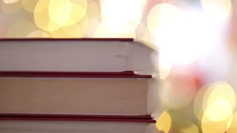 Stack of books close-up against a background of golden bokeh. Cozy reading Видео 334459684