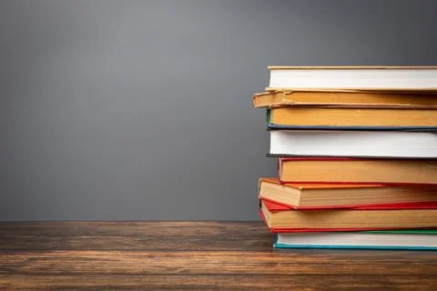 A stack of books in a colored cover and a book with old pages on a gray bac.. Stock Photos