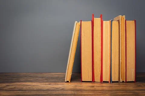 A stack of books in a colored cover and a book with old pages on a gray bac.. Stock Photos