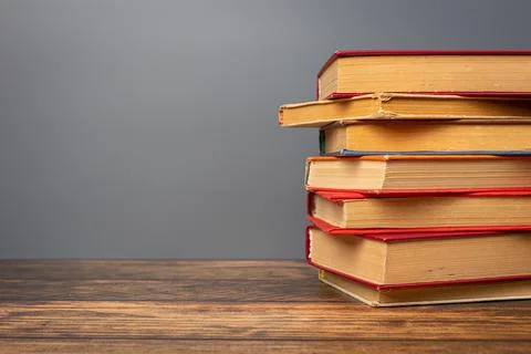 A stack of books in a colored cover and a book with old pages on a gray bac.. Foto stock