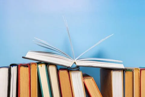 Stack of books in the colored cover lay on blue backround. Education learni.. 스톡 사진