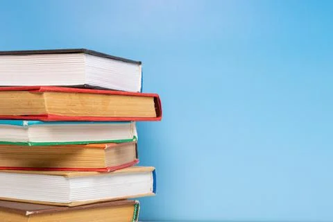 Stack of books in the colored cover lay on blue backround. Education learni.. Stock Photos