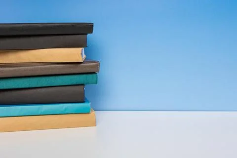 Stack of books in the colored cover lay on the wooden  table and blue backr.. Stock Photos