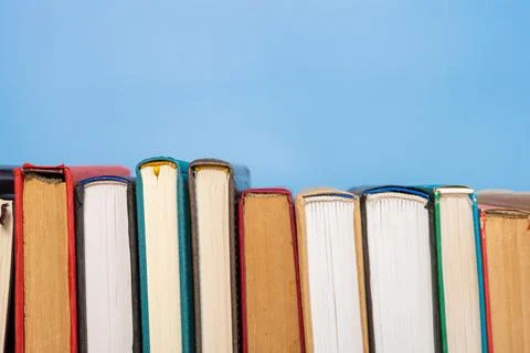 Stack of books in the colored cover lay on blue backround. Education learni.. 스톡 사진