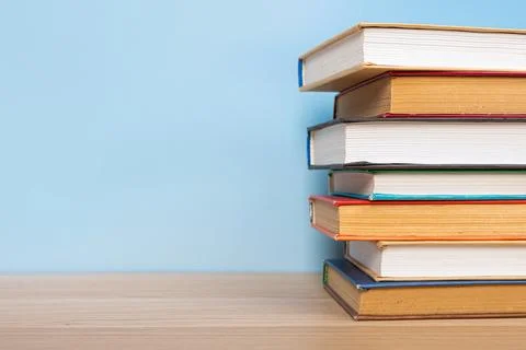 Stack of books in the colored cover lay on the wooden  table and blue backr.. Foto stock
