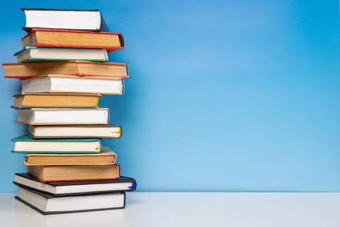 Stack of books in the colored cover lay on the wooden  table and blue backr.. Stock Photos