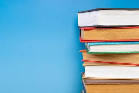 Stack of books in the colored cover lay on blue backround. Education learni.. Stock Photos