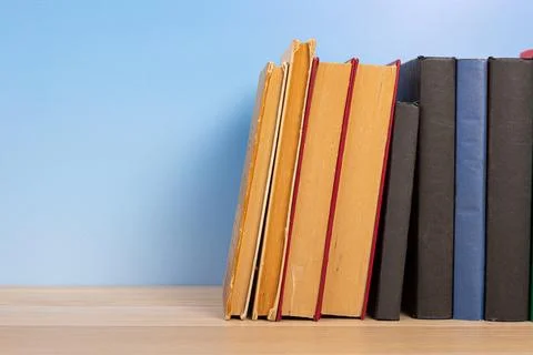 Stack of books in the colored cover lay on the wooden  table and blue backr.. Stock Photos