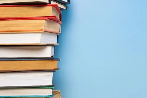Stack of books in the colored cover lay on blue backround. Education learni.. Stock Photos