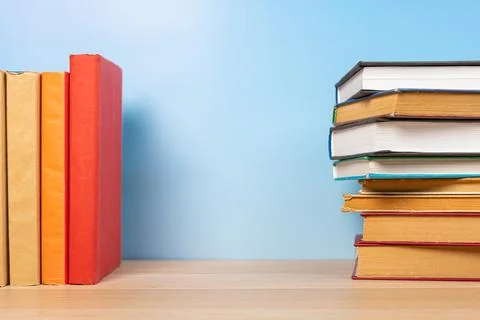 Stack of books in the colored cover lay on the wooden  table and blue backr.. Foto stock