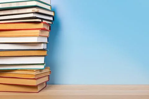 Stack of books in the colored cover lay on the wooden  table and blue backr.. 스톡 사진