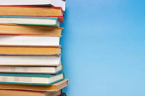 Stack of books in the colored cover lay on blue backround. Education learni.. Stock Photos