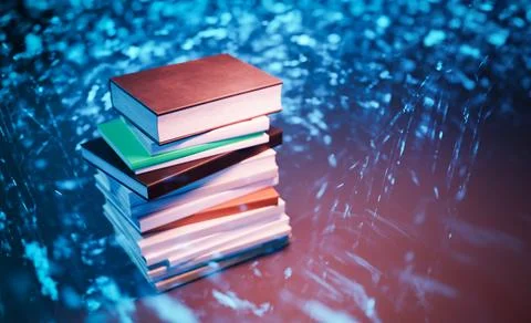 Stack of books with colorful covers against glowing abstract background Photos