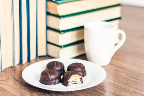 Stack of books, cup of coffee and chocolate cookies white plate. Stock Photos