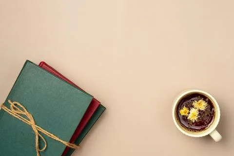 Stack of books with cup of herbal tea on a beige background. Leisure concept, Stock Photos