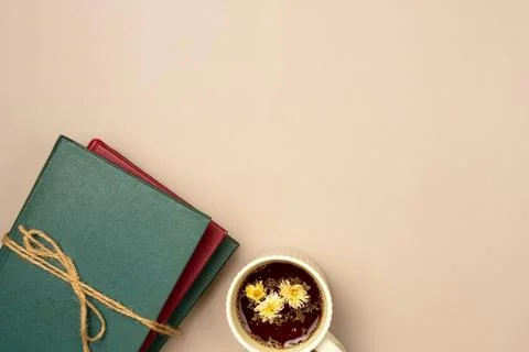 Stack of books with cup of herbal tea on a beige background. Leisure concept, Stock Photos