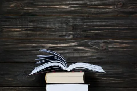 Stack of books with dark wooden background. Free space for text Stock Photos