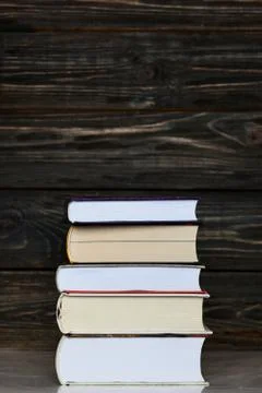 Stack of books with dark wooden background. Vertical orientation Stock Photos