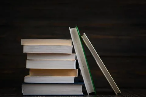 Stack of books with dark wooden background. Stock Photos
