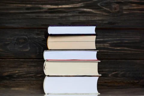 Stack of books with dark wooden rustic background. Stock Photos