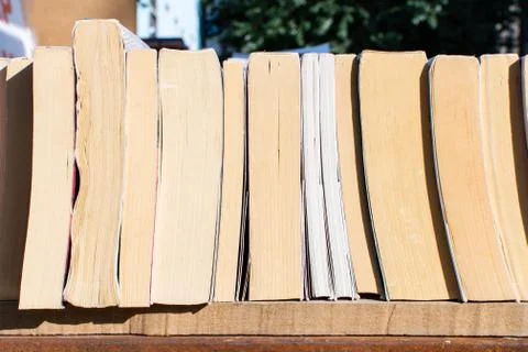 Stack of books of different size on the shelf. Stock Photos